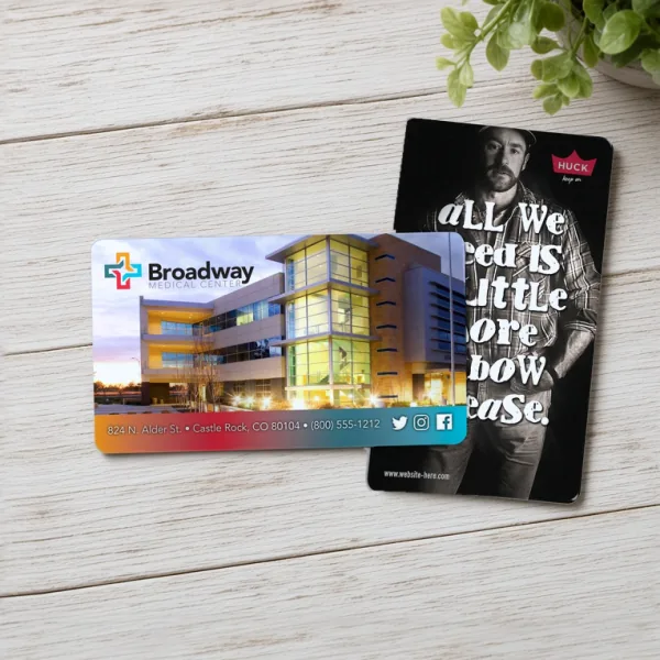 Two custom printed magnets, a Broadway Medical Center photo design and a black-and-white HUCK design, beside a plant.