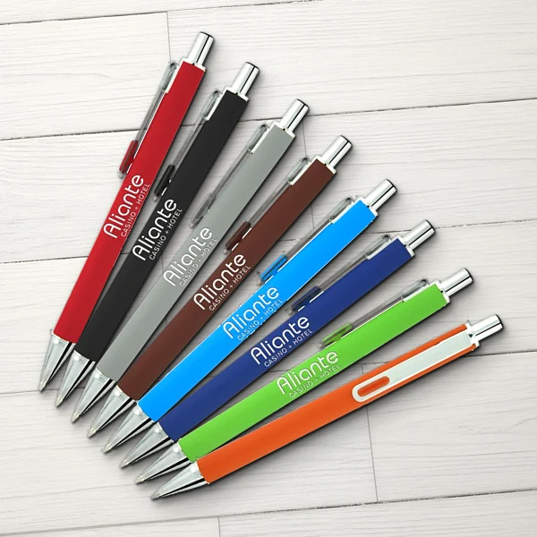 Custom printed soft-touch click pens in red, black, gray, brown, light blue, navy, lime green and orange, fanned out on whitewashed wood, with a white casino and hotel logo imprint, by Captain Notepad.