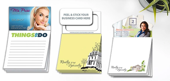 Three notepads with business card holder slots, to-do list designs, and real estate agent branding on white paper.