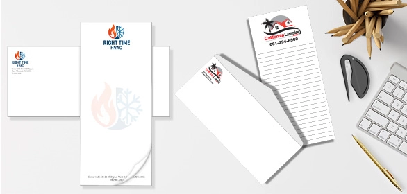 Notepads and envelopes printed with HVAC and real estate logos arranged on a desk with pencils and keyboard.