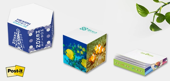 Two printed paper cubes with hexagon and tropical fish designs beside a rainbow edged sticky note pad.