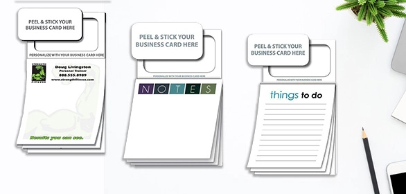 Three white notepads with peel-and-stick business card tabs at the top, beside a yellow pencil and small green plant on desk.