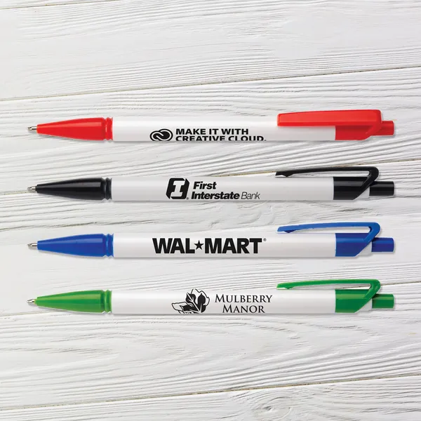Four click pens in red, black, blue, and green with white barrels, promotional product samples on wood surface