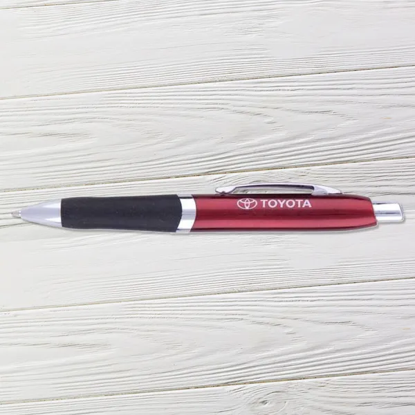 Red and black ballpoint pen with chrome accents on whitewashed wood surface