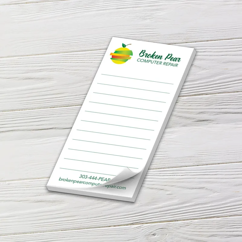Custom 2 x 4 inch lined mini notepad with a pear logo for a computer repair shop, top sheet curling, on white wood