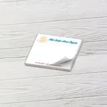 Custom 4 x 3 inch landscape memo pad with a script auto repair logo, top sheet curling, on white wood