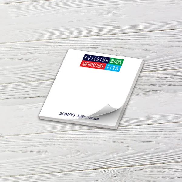 Custom 4 x 4 inch square notepad with a colorful block letter logo, top sheet curling, on white wood