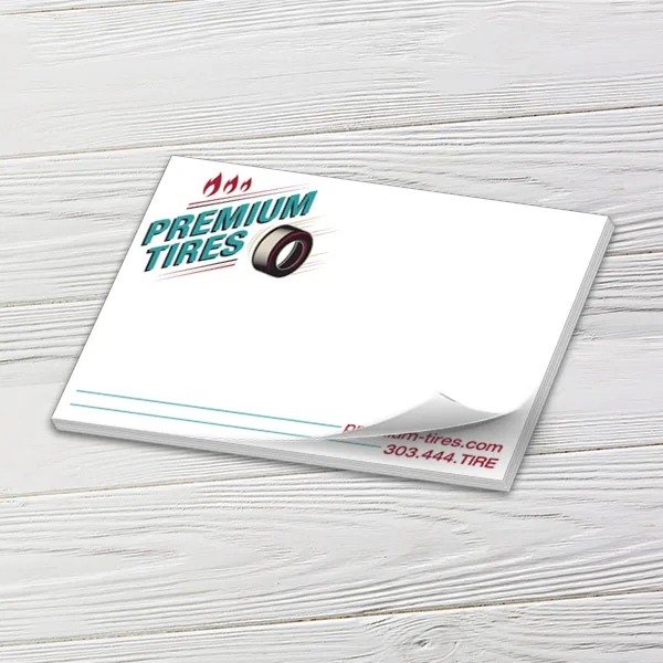Custom 6 x 4 inch horizontal notepad with a Premium Tires logo, top sheet curling, on white wood