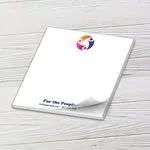 Custom 6 x 6 inch large square notepad with a colorful nonprofit logo and web address, on white wood