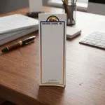 Custom 2 x 6 inch construction company narrow notepad standing on a desk beside a keyboard and a pen