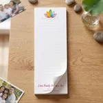 Custom 3 x 8 inch lined wellness center notepad with lotus logo, top sheet curling, on a wood table with photos and stones