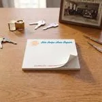 Custom 4 x 3 inch auto repair memo pad lying flat on a wood desk beside car keys and a framed photo