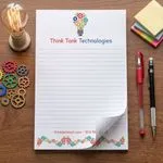 Custom 5.5 x 8.5 inch Think Tank Technologies lined notepad flat beside an Edison bulb and gears