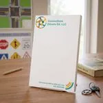 Custom 6 x 9 inch Connections Drivers Ed notepad on a stand in a classroom with road signs