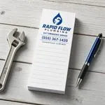 Custom 2 x 4 inch plumbing company notepad with logo, 24/7 service line and lined page, beside a wrench and a blue pen